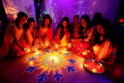 Indian women light lamps around a colourful Rangoli decoration that they made on the eve of Diwali festival celebrations in Bhopal, India on Tuesday. Sanjeev Gupta / EPA