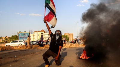 A Sudanese protester holds a national flag as thousands of people march during nationwide demonstrations following the military takeover. EPA / STR