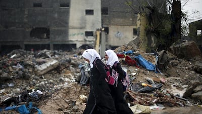 Palestinian schoolgirl walk past the rubble of a house that witnesses said was destroyed by Israeli shelling during a 50-day war in 2014 summer, on a rainy day in Beit Hanoun town in the northern Gaza Strip April 12, 2015. Suhaib Salem/Reuters