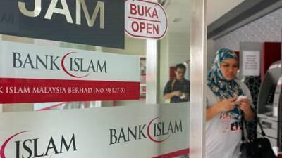 A Muslim customer exits a branch of BIMB Holdings Bhd., formerly known as Bank Islam Malaysia Bhd., in Kuala Lumpur, Malaysia, on Saturday, Sept. 25, 2010. BIMB Holdings provides all aspects of Islamic banking services. Photographer: Goh Seng Chong/Bloomberg