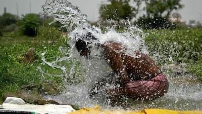 A man takes a shower in water pouring from a pipe in Delhi's Yamuna flood plains. Temperatures in the Indian capital have soared to a record high of 49.9°C. AFP