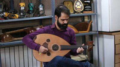 Iranian musical artist and instructor Hamid Khansari tests an instrument at luthier Fatemeh Moussavi's workshop in Tehran. AFP