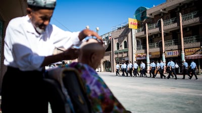 A police patrol passes a barber near the Id Kah Mosque in the old town of Kashgar, in China's Xinjiang Uighur Autonomous Region, after the morning prayer on Eid Al Fitr on June 26, 2017. Johannes Eisele / AFP