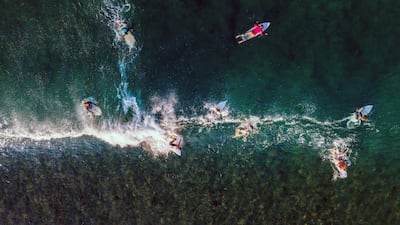 Surfers ride a wave at Lhoknga Beach, in Indonesia's Aceh province. AFP