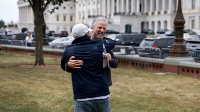 Stewart hugs 9/11 advocate John Feal. Getty Images / AFP