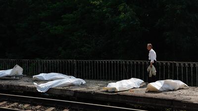 A man walks past bodies in plastic bags of people killed during a Russian ballistic missile and drone strikes at a railway station in the Kyiv region. AFP