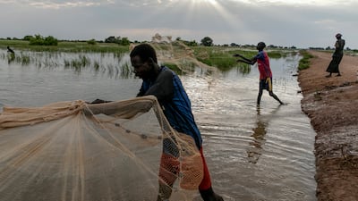 Fisherman Daniel Deng casts his net along the road leading to Malualkon. He said the flood is "the worst thing that's happened in my lifetime".