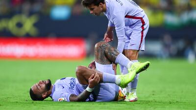 Memphis Depay is helped by Barcelona teammate Ricard Puig after falling to the pitch. Getty Images