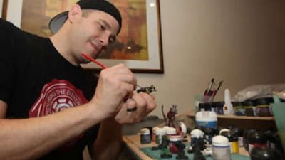 Trevor Van Cleave paints his collection of Warhammer warrior figurines at his house in Dubai.
