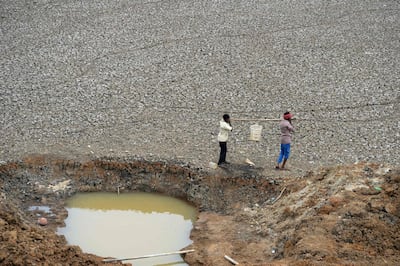 Two men collect water from a small pond in the dried-out Puzhal reservoir on the outskirts of Chennai. AFP