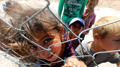 Displaced children from ISIL's Syrian stronghold of Raqqa pose for a photo behind a fence at a camp in Ain Issa on August 22, 2017. A charity said children escaping Raqqa have been "tormented" by years of living under ISIL. Delil Souleiman / AFP