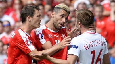Stephan Lichtsteiner and Valon Behrami of Switzerland talk to Jakub Blaszczykowski of Poland. CJ Gunther / EPA