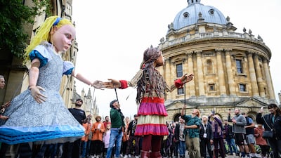 Little Amal and Alice in Wonderland greet children in the city centre of Oxford as part of The Walk, a cross-border project highlighting the plight of unaccompanied child refugees. Getty Images