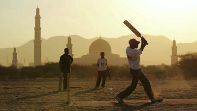 Locals play a cricket match behind the Sultan Qaboos Grand Mosque. Getty Images