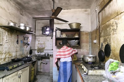 A man cooks in his shared home kitchen in Maysaloon, Sharjah, near where a woman and her son died in a fire on Monday. Reem Mohammed / The National