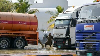 Workers pump floodwaters from the roads into tankers in Fujairah city. Khushnum Bhandari / The National