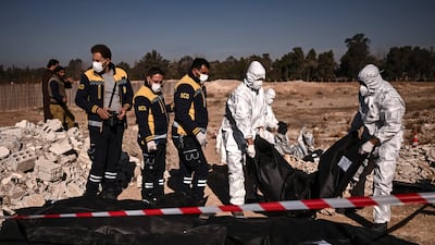 Members of the White Helmets lift bags containing human remains from a mass grave in Damascus. AFP