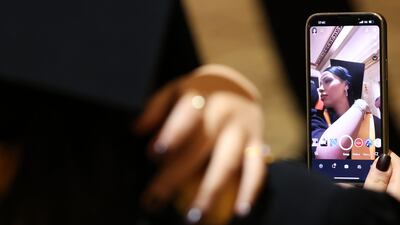 A graduate uses their phone to sort her hair before going on stage