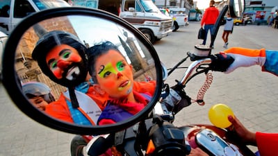 Clowns are reflected in a motorcycle's mirror. AFP