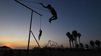 A gymnast performs on the rings as the sun sets at the original Muscle Beach in Santa Monica, California. Mark Ralston / AFP Photo
