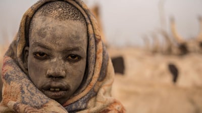A Sudanese boy covers his face in ash from a burned cow dung to keep away mosquitos.