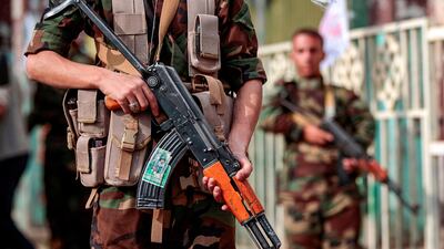 A fighter loyal to Yemen's Houthi rebels holds a Kalashnikov assault rifle showing a picture of other slain comrades as he stands guard during a rally commemorating the Shiite Muslim religious holiday of Ashura in the capital Sanaa. AFP