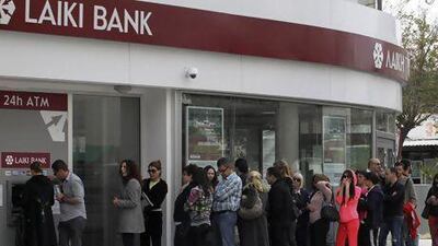 People queue up to make a transaction at an ATM outside a branch of Laiki Bank in Nicosia yesterday. Andreas Manolis / Reuters