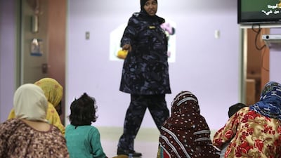 Women and their children eat lunch and spend their time together, as a correctional officer walks by.