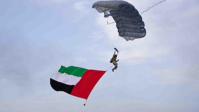 A parachute trails a UAE flag in the sky. WAM