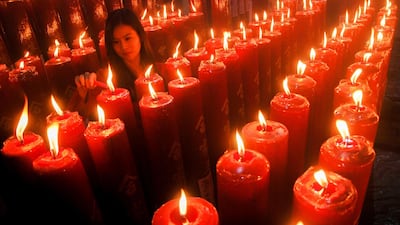 A woman lights a candle in Bandung, West Java province. Timur Matahari / AFP Photo