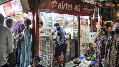 Advertisements for Bharti Airtel Ltd. are displayed above customers at a mobile phone store in Mumbai, India. Telecoms is one sector in which foreign direct investment declined. Bloomberg