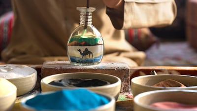 A sand artist can customise vibrant jars with motifs such as camels, birds and sunsets in the desert