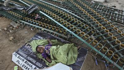 A child sleeps in the shade of a flyover as her mother works at a construction site on a hot summer day in Jammu. Channi Anand / AP Photo