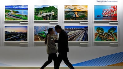 People walk by a display board showcasing China's construction projects at the media centre. AP Photo