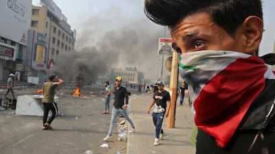 A protester wearing an Iraqi national flag as a face mask stands during clashes between protesters and riot police in Baghdad's central Tahrir Square. AFP