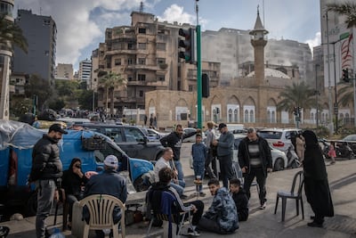 Displaced people sit on the roadside as smoke rises from a building hit by an Israeli air strike on Beirut in April. Getty Images