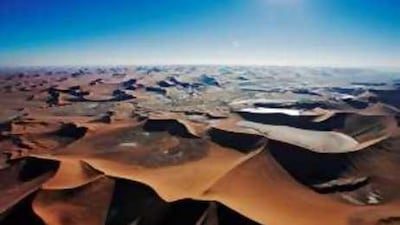 An aerial view of the tan valleys in the Namib Desert. The sensitively designed Sossusvlei Mountain Lodge is sculpted to blend in with the landscape.