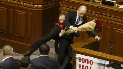 Legislator Oleg Barna removes prime minister Arseny Yatseniuk from the tribune, after presenting him a bouquet of roses, during the parliament session in Kiev. Valentyn Ogirenko / Reuters