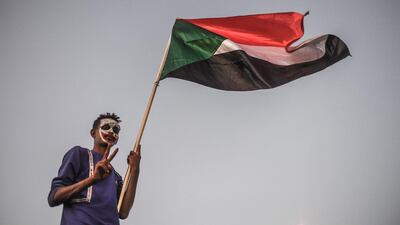 A Sudanese protester waves a national flag outside the army complex in Khartoum. Ozan Kose / AFP