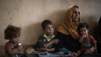 Iraqi civilians sit inside a house as they wait to be taken out of the Old City during fighting between Iraqi forces and ISIL militants in Mosul on Sunday. AP / Felipe Dana