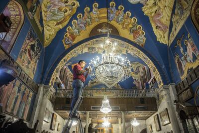 Rami Ayyad stands carefully cleans each crystal from a chandelier hanging in the Church of Saint Porphyrius in Gaza city. Photo by Heidi Levine for The National
