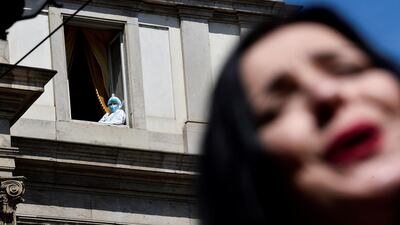 A person wearing a protective suit looks out from a window as an opera singer performs outside La Scala theatre as part of a protest to highlight the entertainment sector's crisis caused by the pandemic and restrictions, in Milan, Italy. Reuters