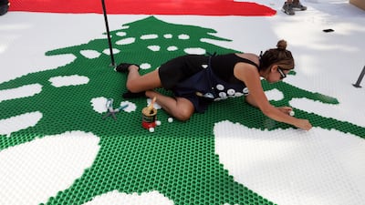 Recycling artist Caroline Chaptini retouches a huge Lebanese flag made from 10,452 bottle caps in Aajaltoun. The number represents the area of Lebanon in square kilometres. EPA