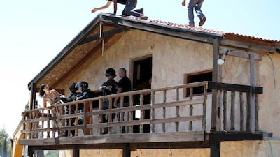Israeli soldiers try to prize the Palestinian woman from the building. EPA