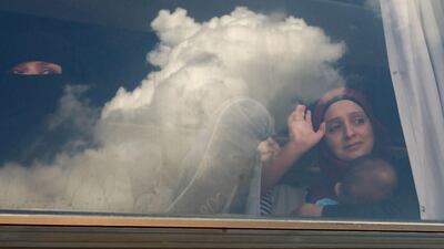Syrian refugees wave through the windows of a bus as they prepare to leave the Lebanese capital Beirut to return to their homes in Syria on September 9, 2018. AFP