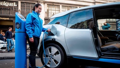 A woman connects a BMW i3 electric car to a charging point. Chinese firm CATL will build a battery plant in Germany. AFP