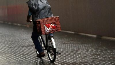 A cyclist shields himself from the rain in Abu Dhabi. Delores Johnson / The National