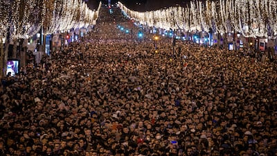 Revellers watch a sound and light show projected on the Arc de Triomphe as they celebrate the New Year on the Champs Elysees, in Paris, on December 31, 2022. AP