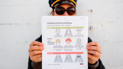A man holds up an information pamphlet about new Austrian restrictions that ban the wearing of burkas and other face coverings in public places and buildings, in Vienna on September 29, 2017. Joe Klamar / AFP