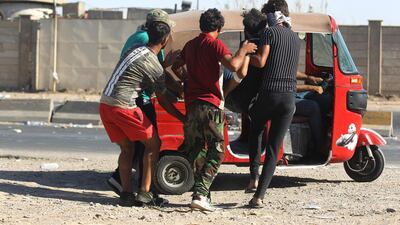 Iraqi men carry a wounded protester into a Tuk Tuk during a demonstration against state corruption, failing public services, and unemployment, in the Iraqi capital Baghdad's central Khellani Square on October 4, 2019. AFP RUBAYE